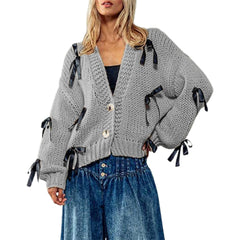 Woman wearing a gray knitted cardigan with black ribbons and blue jeans