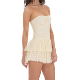 Woman wearing a strapless, ruffled cream dress - side view