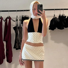 Person taking a mirror selfie wearing a black and white polka dot outfit in a clothing store.