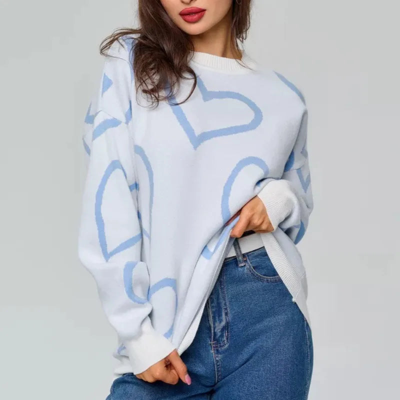 Person wearing a light blue sweater with heart patterns and blue jeans
