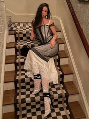 Woman sitting on a staircase with a checkered floor, wearing a black and white outfit.