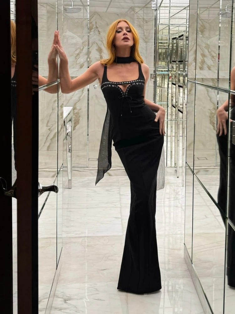 Woman in a black dress standing in a modern hallway with glass walls.