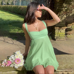 Woman in a green dress holding flowers outdoors