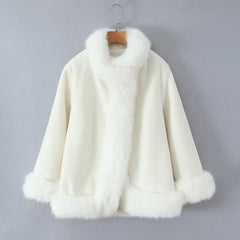 White fur coat on a hanger against a gray background