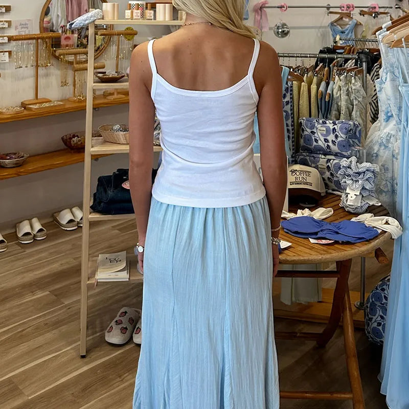Woman wearing a white top and light blue skirt in a store setting