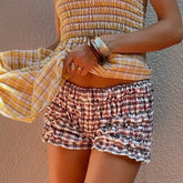 Person wearing a plaid outfit with a yellow and brown top and shorts against a plain background