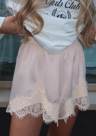 Person wearing a white lace-trimmed skirt over a white t-shirt with text.