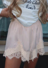 Person wearing a white lace-trimmed skirt over a white t-shirt with text.