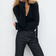 Person wearing a black sweater and dark jeans against a white background