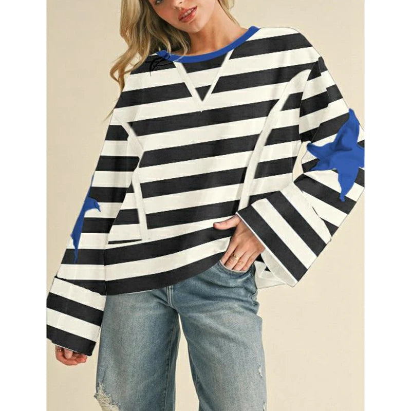 Person wearing a black and white striped sweater with blue accents on a beige background