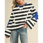 Person wearing a black and white striped sweater with blue accents on a beige background