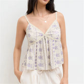 Woman wearing a floral spaghetti strap top against a plain background