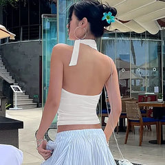 Woman wearing a white top and light blue skirt in an outdoor setting