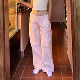 Person wearing light pink lace pants and a white top in a kitchen.