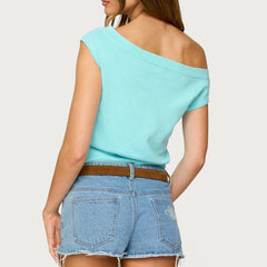 Woman wearing a light blue off-shoulder top and denim shorts