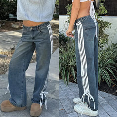 Person wearing blue jeans with white stripes on a stone path.