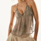 Beige tank top with floral bead embellishments on a plain background
