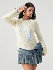 Woman wearing a cream sweater with a blue design and denim skirt on a light gray background