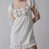 White dress with floral embroidery on a plain background