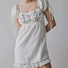 White dress with floral embroidery on a plain background