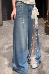 Person wearing blue jeans with decorative elements on a marble floor.