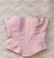 Pink corset with a bow on a textured beige surface