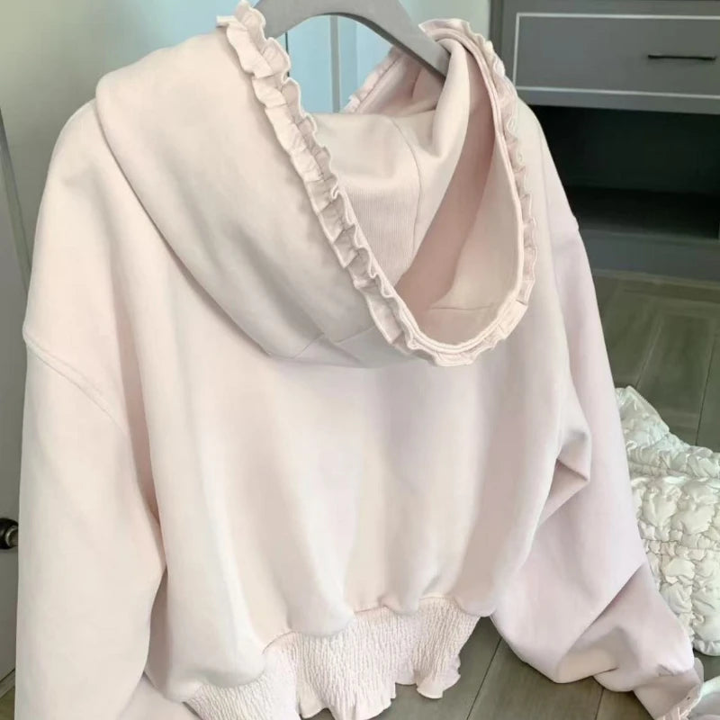 Light pink blouse with ruffled collar and cuffs on a hanger.