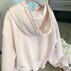 Light pink blouse with ruffled collar and cuffs on a hanger.
