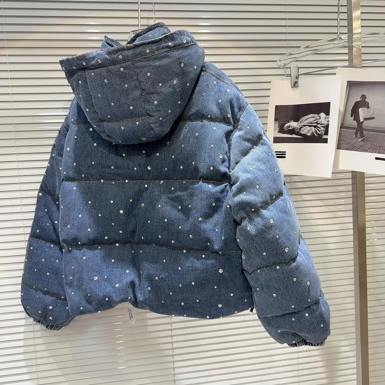 Blue puffer jacket with white polka dots on a hanger against a window background