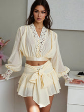 Woman wearing a beige outfit with lace details in an indoor setting.