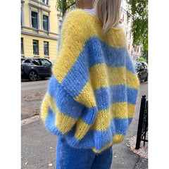 Person wearing a blue and yellow striped sweater on a street.