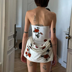Person wearing a white strapless dress with floral patterns in a room.