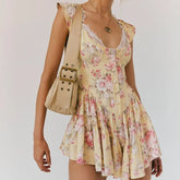 Woman wearing a floral dress holding a beige handbag