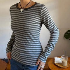 Person wearing a gray and black striped long-sleeve shirt with a plain background