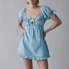 Light blue dress with floral embroidery on a gray background