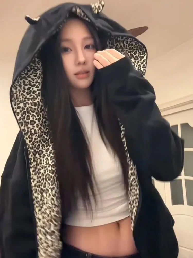 Person wearing a black hoodie with leopard print sleeves and a white top underneath.