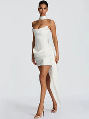 Woman wearing a white strapless dress with a high slit on a plain background