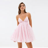 Pink flare cami mini dress with a v-neck and adjustable strap tie-up back, shown on a diverse model, front view.