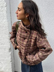 Woman wearing a plaid jacket against a white wall