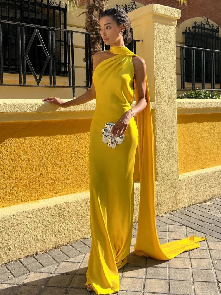 Woman in a yellow evening gown standing against a yellow wall.