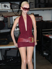 Person wearing a burgundy dress with a belt in an indoor setting