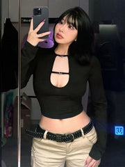 Person wearing a black long-sleeve top with cut-out design and beige pants, taking a mirror selfie.