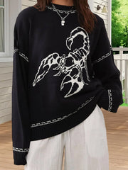 Person wearing a black sweater with a white scorpion design outdoors.
