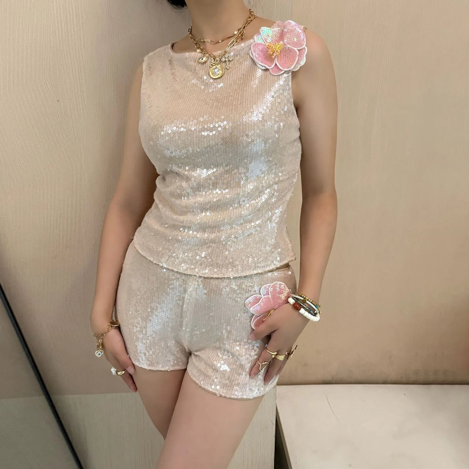 Person wearing a sparkly outfit with floral accessories against a neutral background