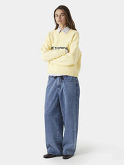 Person wearing a light yellow sweater and blue jeans