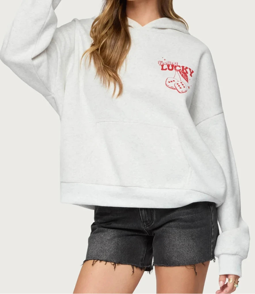 Person wearing a white hoodie with a red graphic and text on a plain background