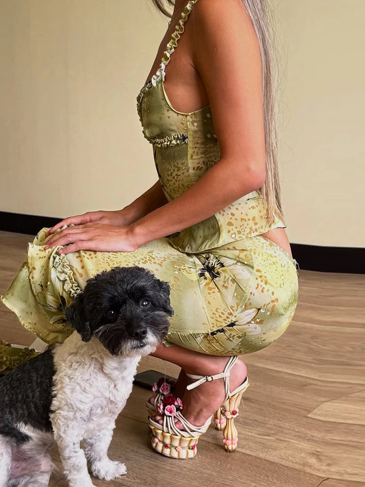 Woman in a floral dress sitting on the floor with a small dog.