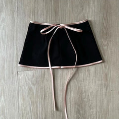 Black skirt with a pink ribbon on a wooden surface