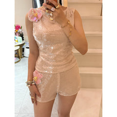 Person wearing a sequined top and shorts set with floral accessories indoors.