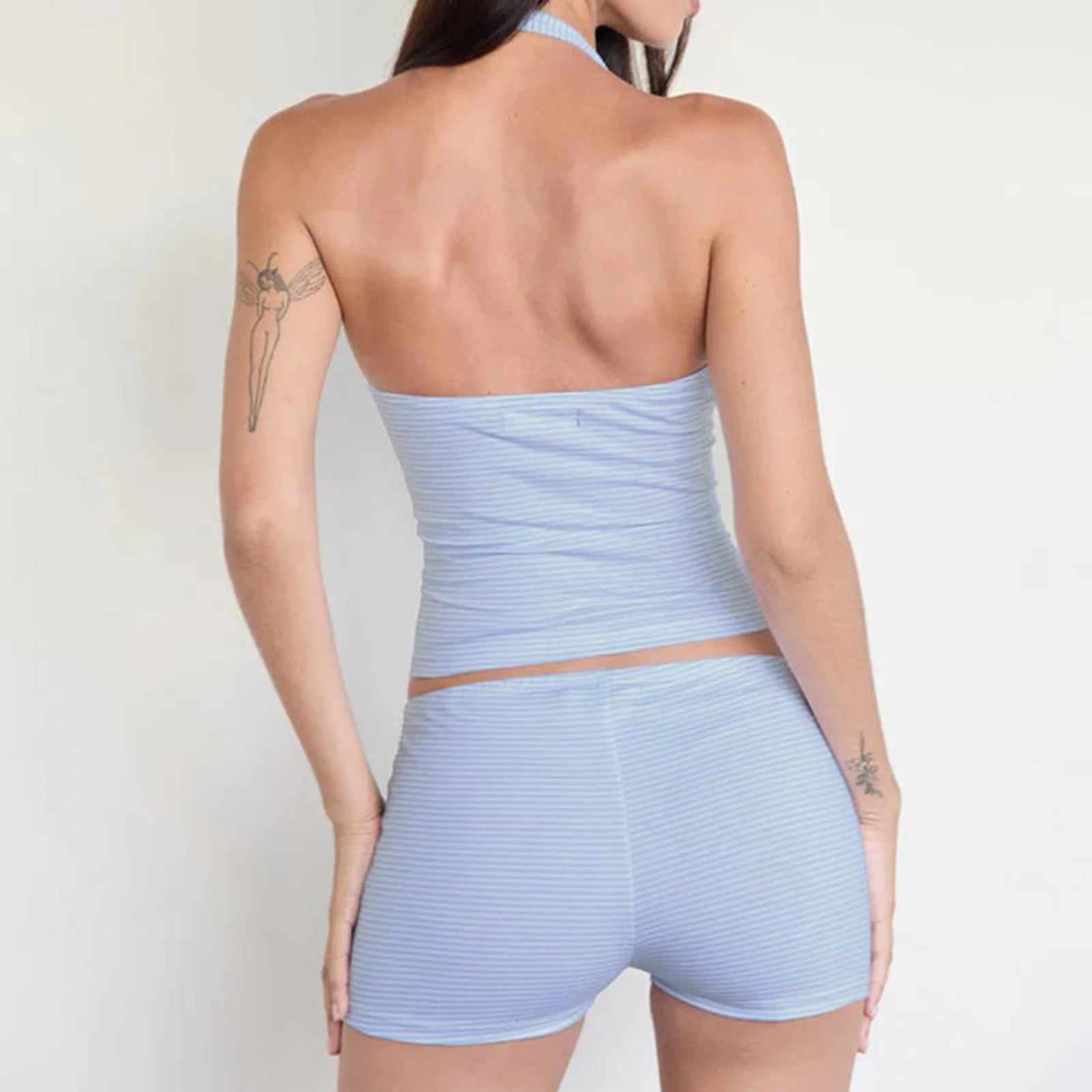 Woman wearing a light blue strapless top and shorts set on a plain background